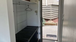 Um espaço pequeno e fechado com um banco de metal, um cabideiro suspenso e um painel de controle.