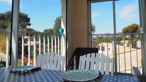 Un balcó amb taula i cadires, una tanca de palets blancs i vista a una zona residencial.