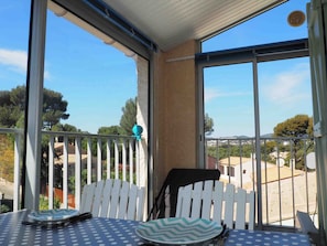 Ein Balkon mit Tisch und Stühlen, ein weißes Zäunchen und Blick auf eine Wohngegend.
