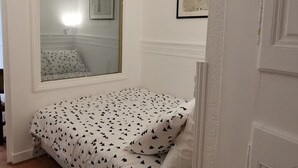 Un dormitorio pequeño con una cama individual, una ventana y un cuadro en la pared.