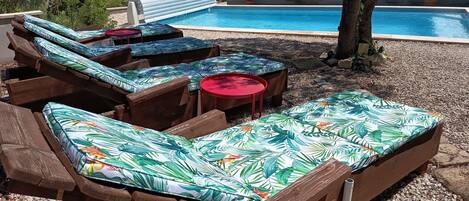 A poolside area with wooden lounge chairs and a small table.