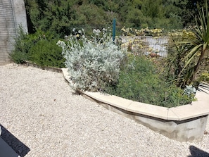A landscaped garden area with a gravel path, various shrubs, and a metal fence. - Entire private gîte (Lédenon)