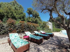 A poolside area with lounge chairs and a building in the background.