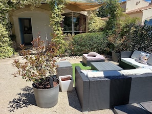 An outdoor seating area with wicker furniture, a potted plant, and a building in the background. - Entire private gîte (Lédenon)