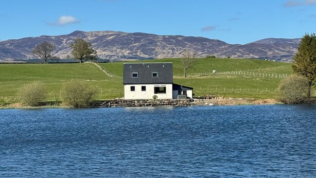 A modern house by a lake with a mountain backdrop. - Wallace Lodge - Unique experience (Comrie)