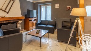 Ein Wohnzimmer mit Fernseher, Sofa, Couchtisch und einer Lampe.