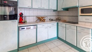 Eine Küche mit weißen Schränken, Türkis-Akzenten, einer roten Kaffeemaschine und einer Mikrowelle.