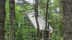 Et moderne glas hus i en skov.