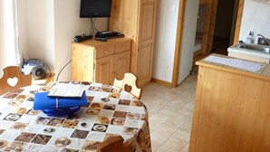 Une petite pièce agréable, dotée d’une table en bois, d’un téléviseur et d’un coin cuisine.