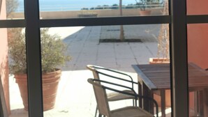 A view through a window with a table and chairs outside, a tree, and a clear sky. - Grand Appartement de 70 m2 vue mer (Saint-Raphaël)