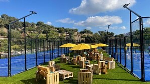 An outdoor seating area with wooden furniture and yellow umbrellas, surrounded by a pool and a fence. - Grand Appartement de 70 m2 vue mer (Saint-Raphaël)