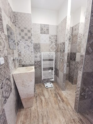 Uma casa de banho com lavatório, chuveiro e sanita.
