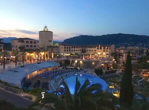 A resort with a large pool, multiple buildings, and a mountainous backdrop.