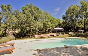 A pool area with lounge chairs and a stone wall. - Luxurious home in Apt (Apt)