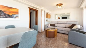Ein modernes Wohnzimmer mit einem Esstisch, grauen Sofas, einem runden Couchtisch und einem Stadtbild an der Wand.