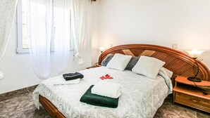 Ein ordentlich bezogenes Bett mit einem gemusterten Bettüberwurf, Kissen und einem gefalteten Handtuch.