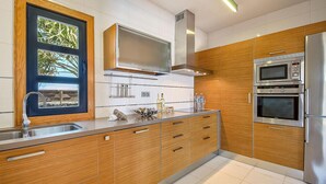 A modern kitchen with wooden cabinets, stainless steel appliances, and a large window with a view.