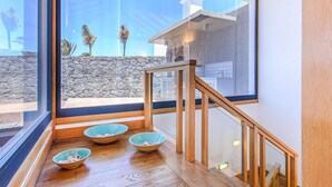 A modern interior with a wooden staircase, a stone wall, and three bowls on the floor.
