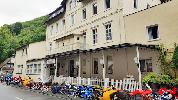 Eine Reihe von Motorrädern vor einem Gebäude mit weißem Zaun.