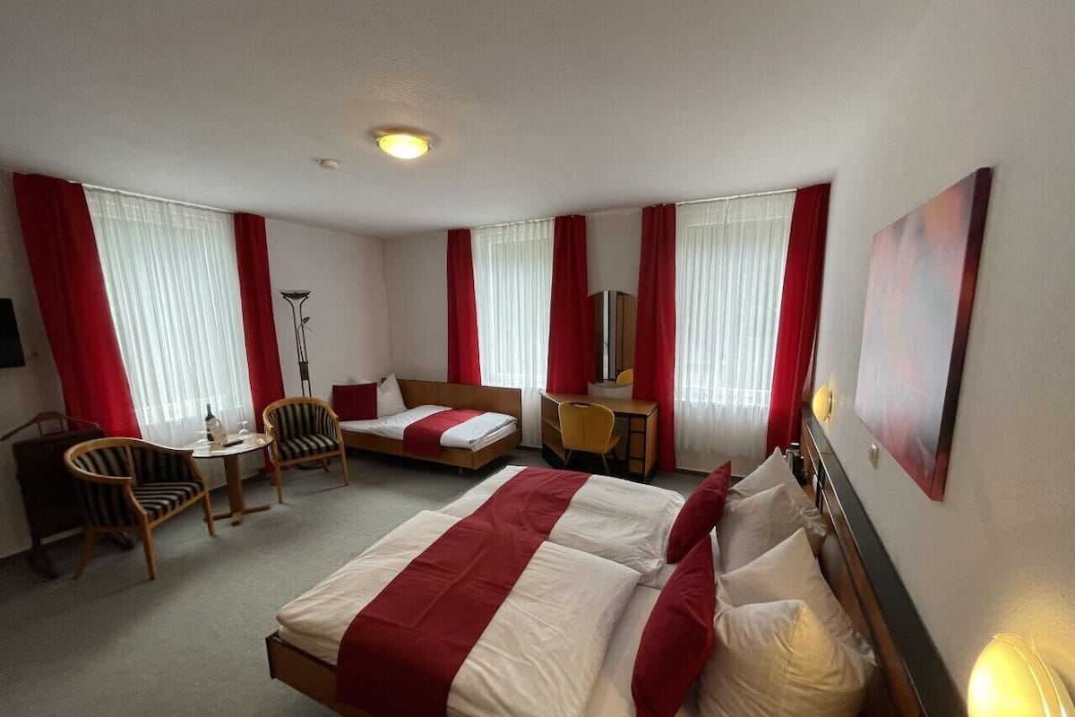 Ein Hotelzimmer mit zwei Betten, einem Schreibtisch, einem Stuhl und einer Lampe.