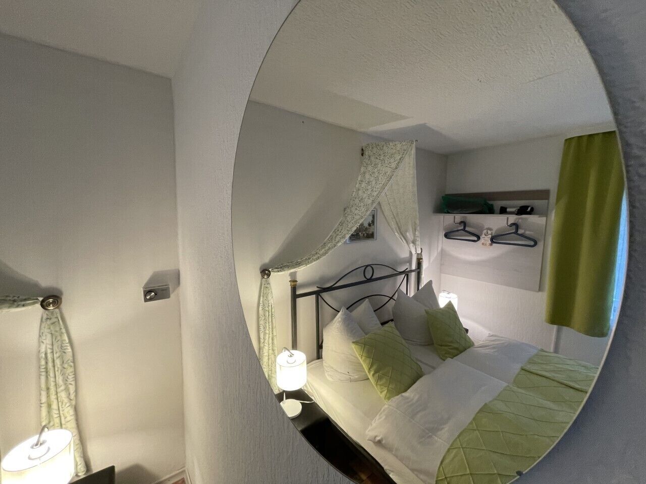 A bedroom with a bed, a bedside table, a lamp, and a mirror.