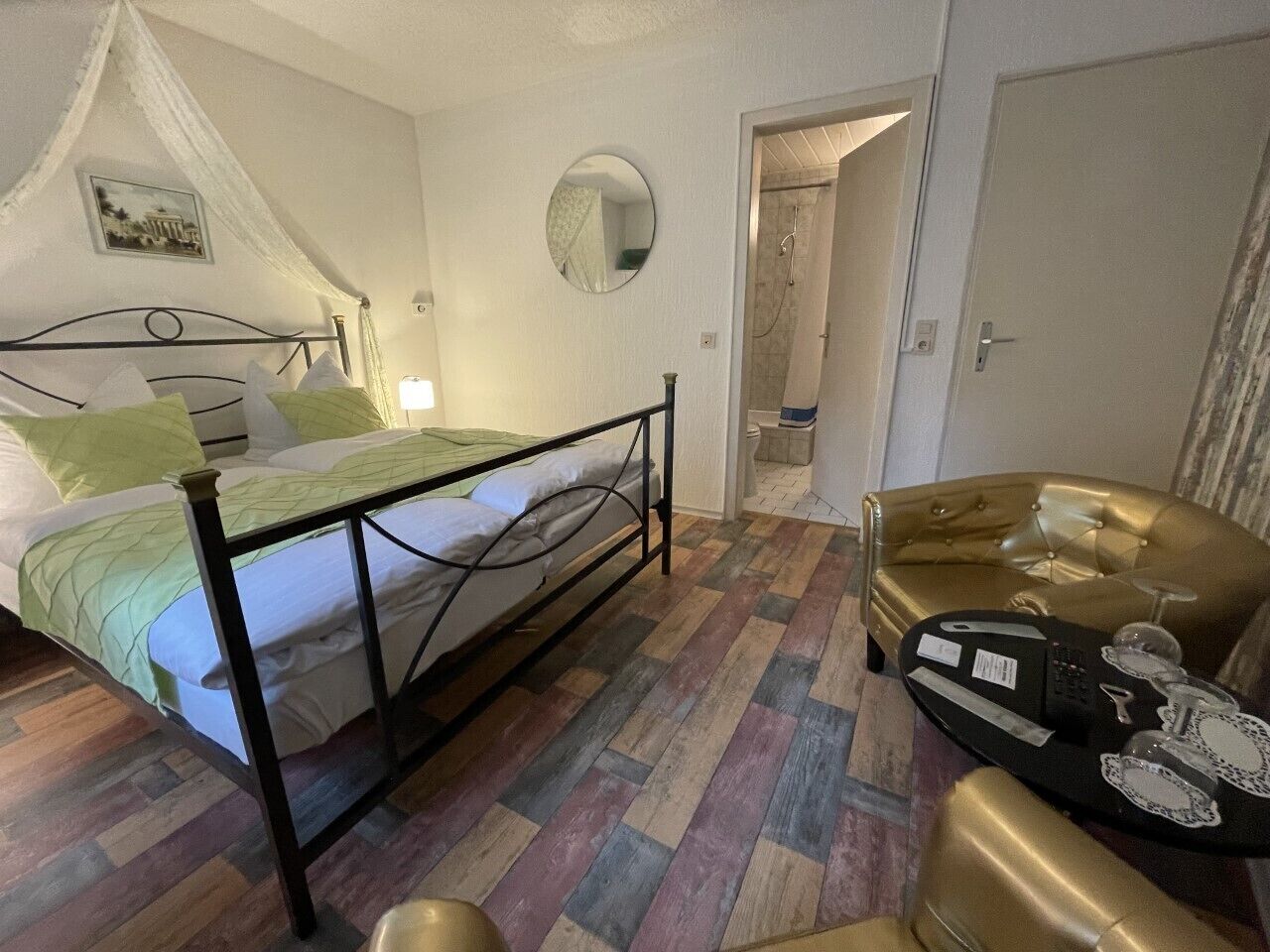A bedroom with a bed, a bedside table, a mirror, and a door leading to a bathroom.