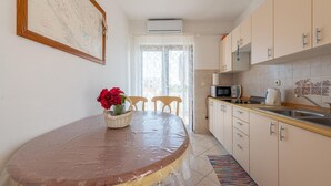 Una cocina con una mesa de comedor, sillas, microondas, hervidor y un lavabo.