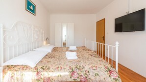 Un dormitorio con cama, televisor, armario y puerta.