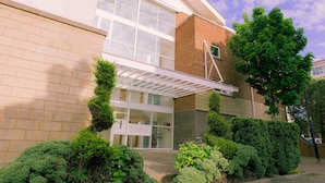 A modern building with a glass entrance, brick walls, and a covered walkway. - Stunning Holiday Stay With Free Gym and Parking (Cardiff)