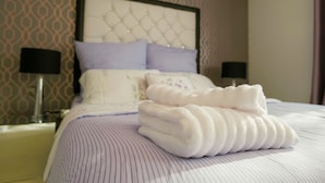 A neatly made bed with a striped bedspread, two pillows, and a folded white towel on top. - Stunning Holiday Stay With Free Gym and Parking (Cardiff)