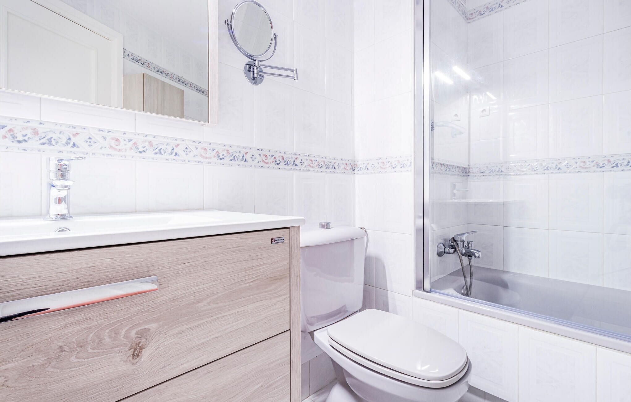 A modern bathroom with a white sink, mirror, and toilet.