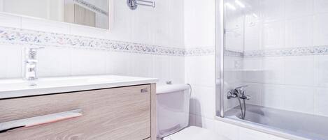 A modern bathroom with a white sink, mirror, and toilet.