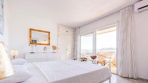 A hotel room with a bed, a dresser, a mirror, and a view of the beach through a large window. - Beach front apartment in Torrox Costa with WiFi (Torrox Costa)