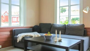 Una sala moderna con un sofá gris, una mesa de centro negra y un bol de frutas.