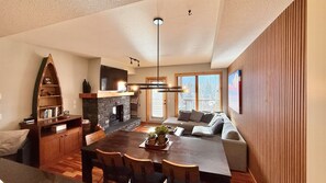 A modern living space with a dining area, fireplace, and a large window providing a view of the outdoors.