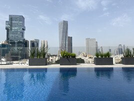 Una piscina al aire libre, sombrillas, sillones reclinables de piscina