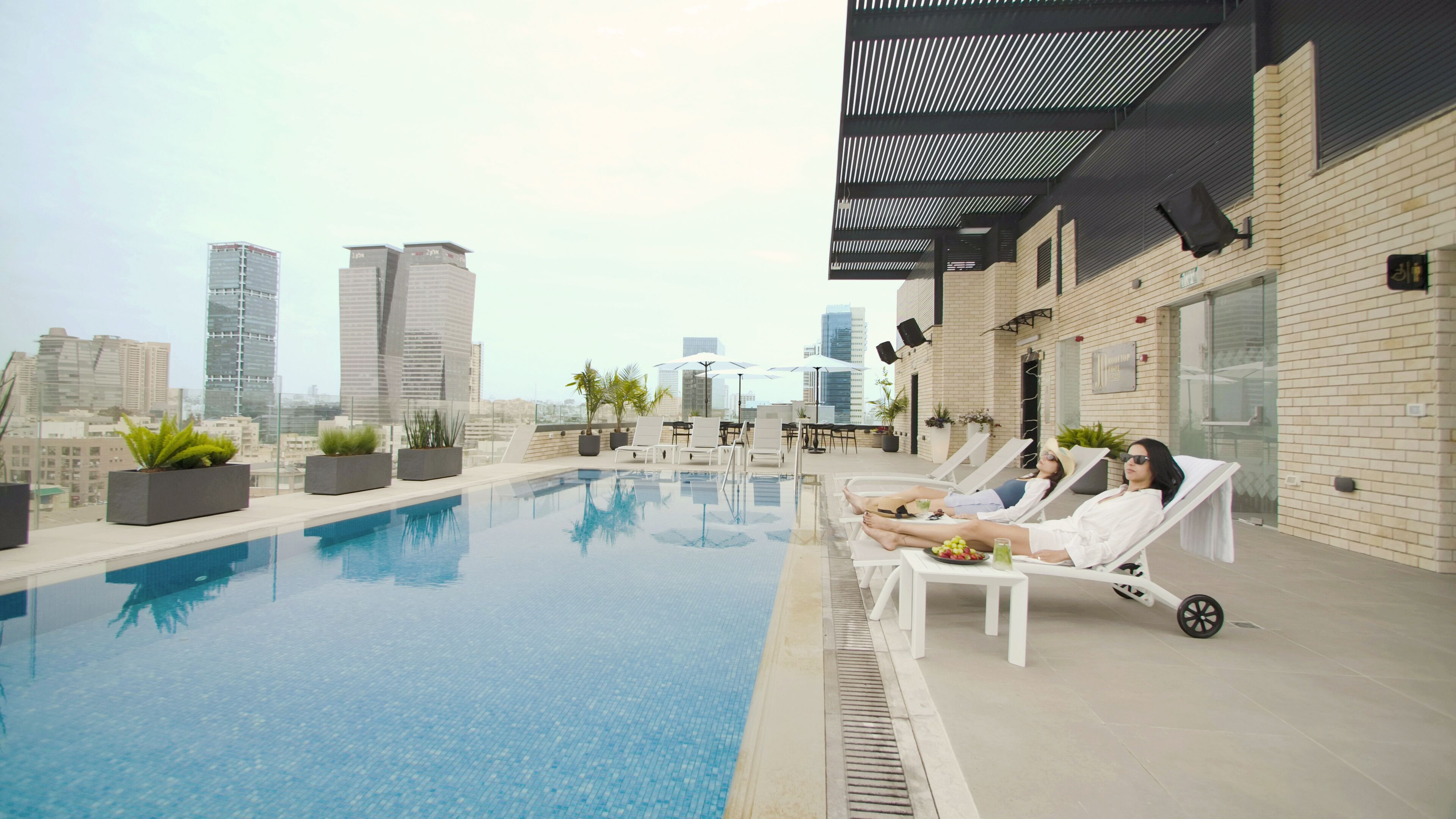 Una piscina al aire libre, sombrillas, sillones reclinables de piscina