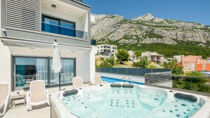 A rooftop pool area with a hot tub, lounge chairs, and a view of a mountainous landscape. - Lovely home in Makarska (Makarska)
