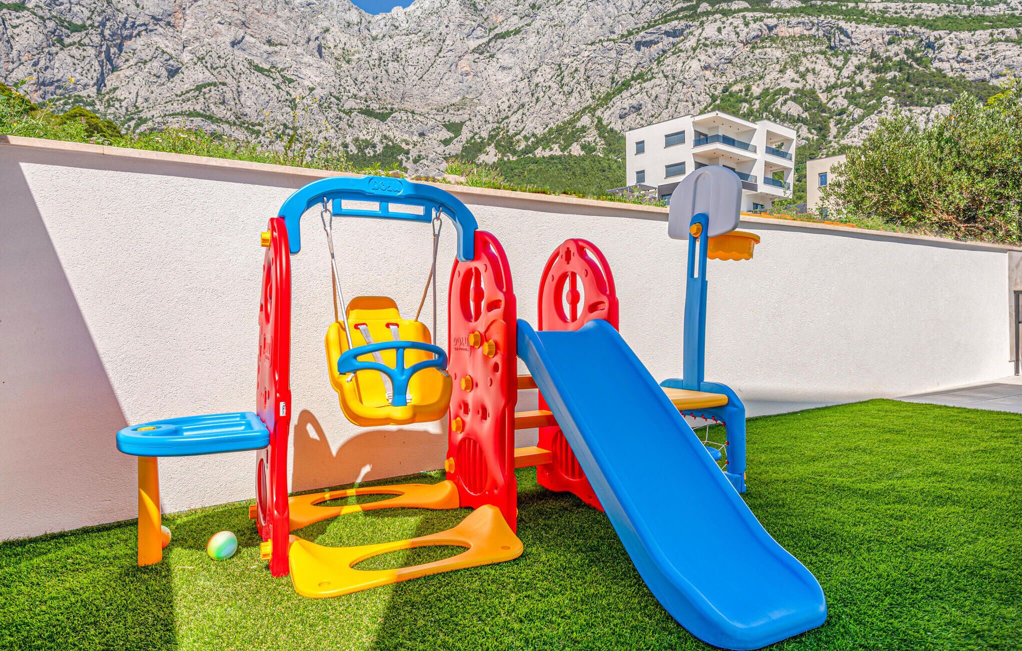 Un espace de jeux pour enfants avec une balançoire, un toboggan et une petite table.