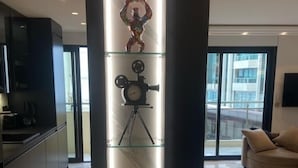 Una sala de estar moderna con un expositor de vidrio que muestra una cámara antigua, un cartel enmarcado y una figurita.
