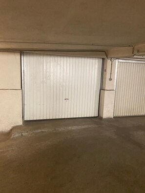 A closed garage door with a metal handle, a concrete floor, and a white wall with a number '6' on it.