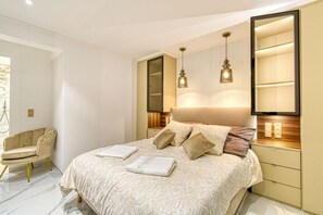 Une chambre moderne avec un grand lit, des tables de chevet, une chaise et un miroir.
