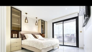 Un dormitorio moderno con una cama grande, un armario y un ventanal corredero que da a un balcón.
