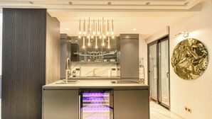 Una cocina moderna con refrigerador empotrado, extractor de acero inoxidable y lámpara colgante.