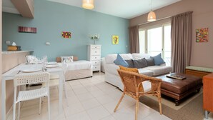 Una habitación moderna y luminosa con una mesa de comedor, sillas, un sofá y una silla de mimbre.