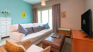 Una sala de estar moderna con un sofá, un reposapiés y un televisor.