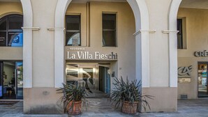 Un edificio con un cartello che riporta "Residence La Villa Fieschi" e un ingresso decorato con due vasi di piante.