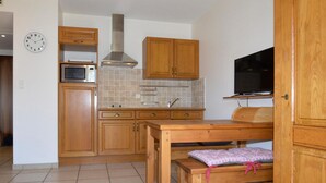 Una cucina compatta con mobili in legno, un forno a microonde, un piano cottura e un'area pranzo con una panca.