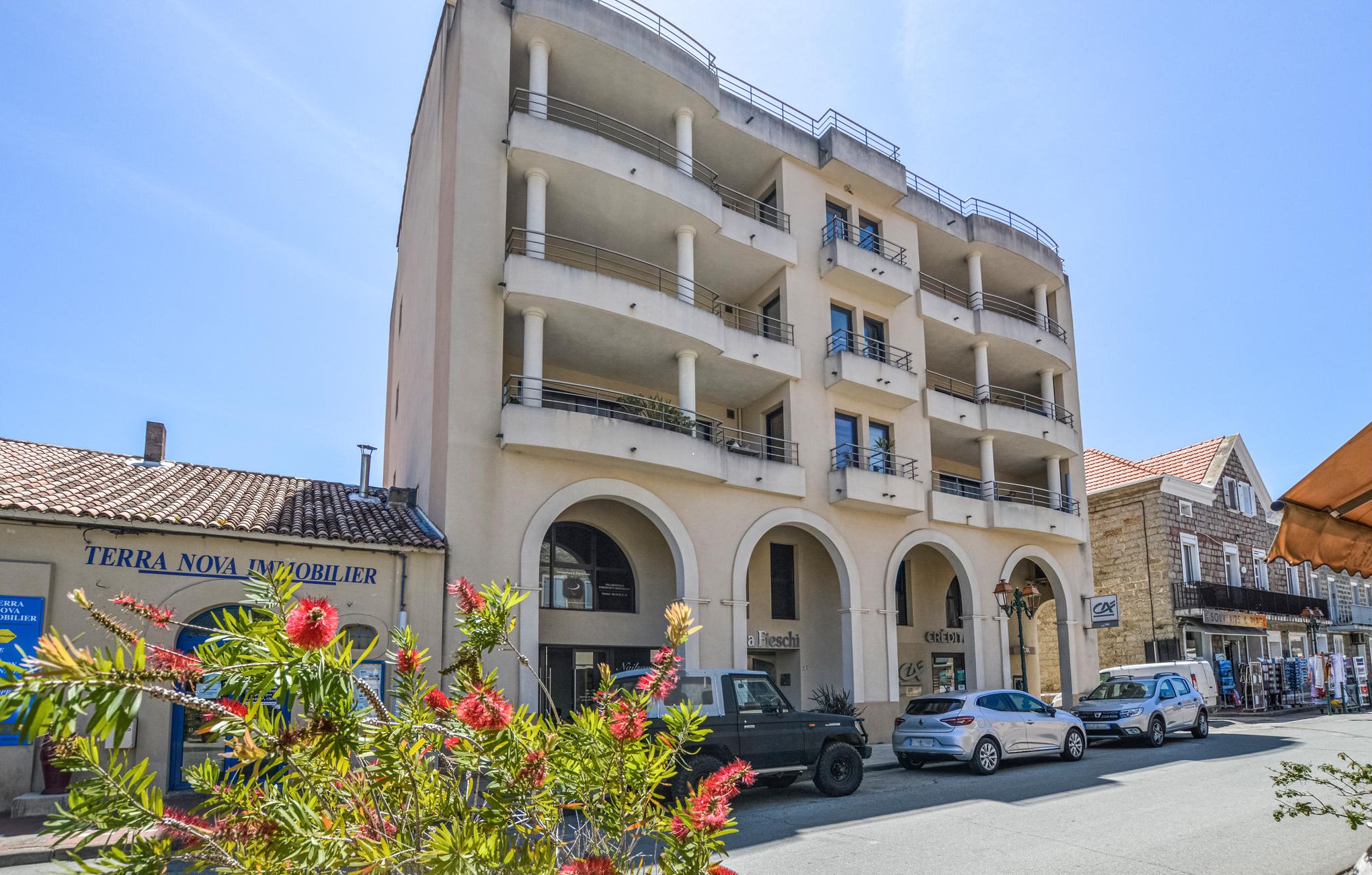 Un hotel de varios pisos con balcones, una entrada visible en la planta baja y un cielo despejado.