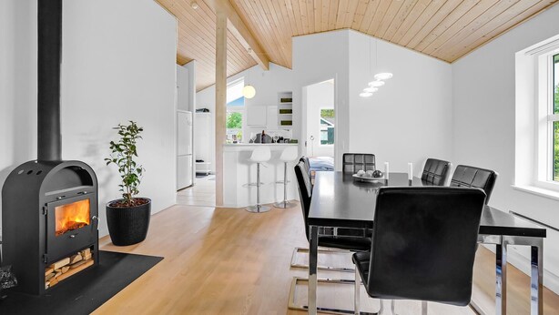 Una cocina moderna con armarios blancos, una estufa negra y una zona de comedor con una mesa y sillas negras.